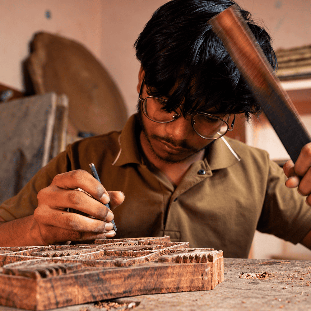 Close-up of carving tools and the actual wooden block, with the artisan working.