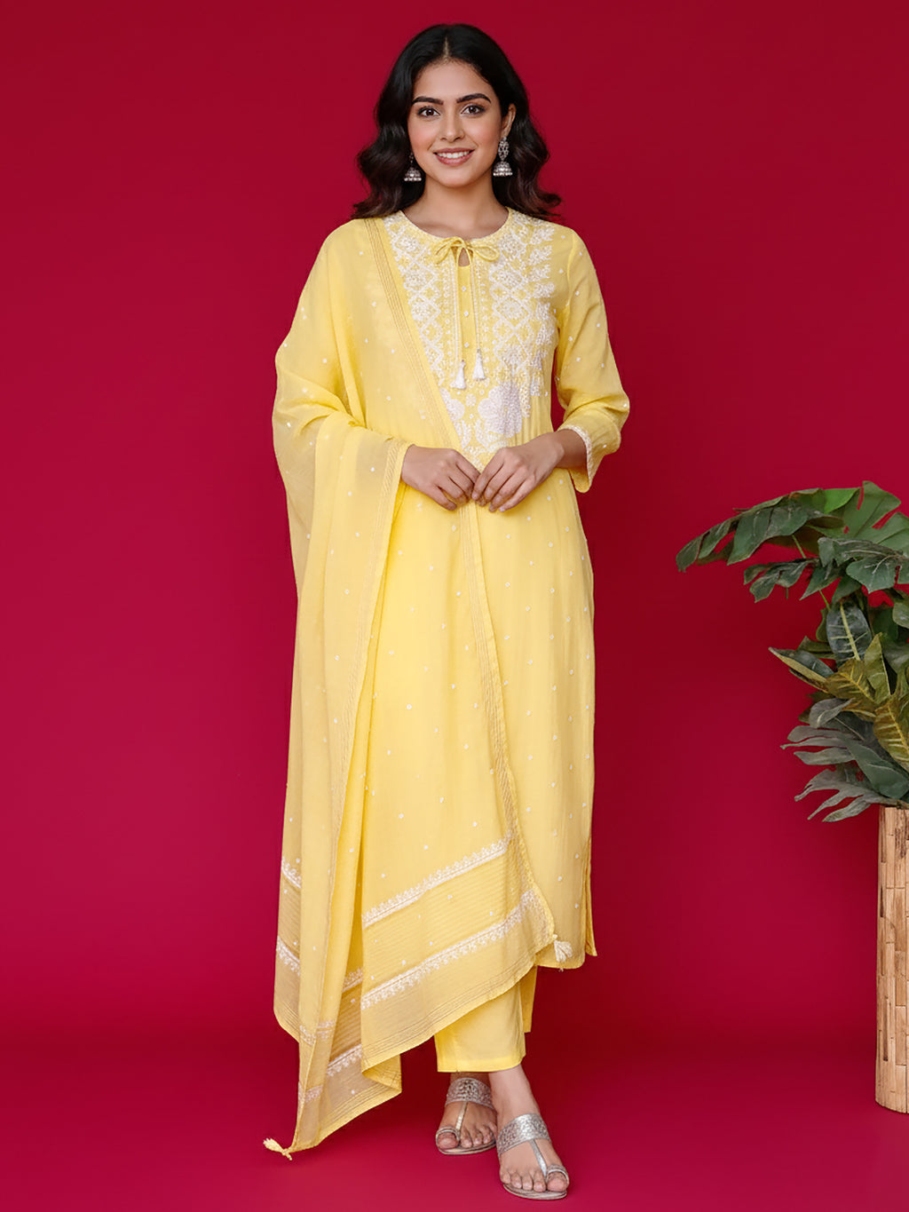 Woman wearing a yellow chikankari outfit with white embroidery on a red background